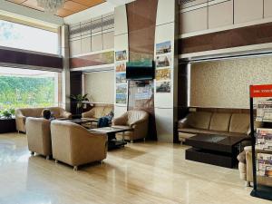 a waiting room with couches and tables and a tv at Hotel President, Pure Veg in Indore