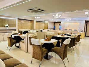 a restaurant with tables and chairs and a man in a room at Hotel President, Pure Veg in Indore