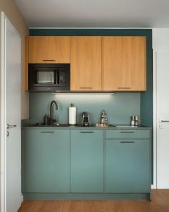 a kitchen with blue cabinets and a microwave at Limehome Berlin Klosterstraße in Berlin