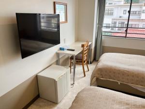 a bedroom with a bed and a desk with a television at Hotel Yamadaso in Nago