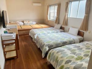 a room with three beds in it with windows at Hotel Yamadaso in Nago +7 photos
