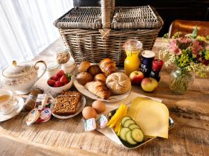 a table with breakfast foods and a basket of food at Onder de regenboog in Egmond aan den Hoef
