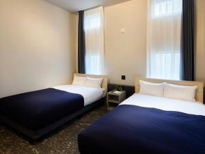two beds in a small room with a window at Minn Sapporo Odori W14 in Sapporo