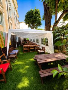 a group of tables and benches under a white canopy at Résidence Les Cordeliers in Avignon