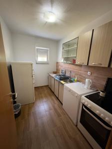 a small kitchen with white appliances and wooden floors at Sobe DANA Banja Vrućica in Teslić