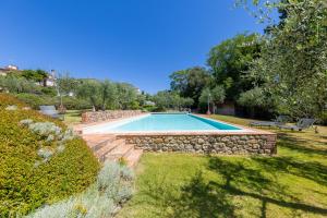 a swimming pool in a yard with a stone wall at Appartamento Rosmarino in Lajatico
