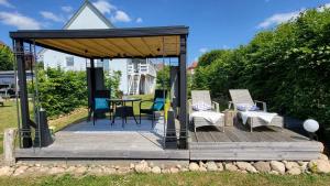 a wooden deck with a gazebo with chairs and a table at Ferienwohnung Seeblick in Klein Upahl