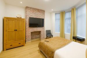 a bedroom with a bed and a brick fireplace at SidemerseyLivings - Step-Free 4BR Home, Ground Floor Bed & Bath, Private Gated Parking in Liverpool