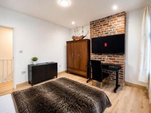 a bedroom with a bed and a desk and a brick wall at SidemerseyLivings - Step-Free 4BR Home, Ground Floor Bed & Bath, Private Gated Parking in Liverpool +24 photos