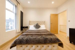 a bedroom with a large bed with a large window at SidemerseyLivings - Step-Free 4BR Home, Ground Floor Bed & Bath, Private Gated Parking in Liverpool