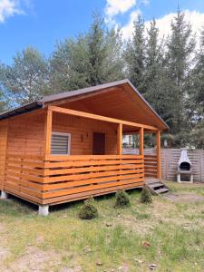 a large wooden cabin in a field with trees at Domki nad Firlejem in Firlej