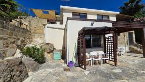 a house with a patio with white tables and chairs at Secluded Garden Studio in Tala
