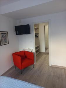 a room with a red chair and a tv on the wall at Casa de la Soledad 2 in Lugo