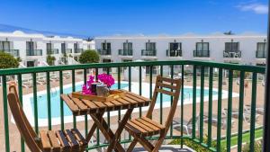 a table and chairs on a balcony with a pool at NEW AVATEA Parque Natural, piscinas y tennis in Corralejo