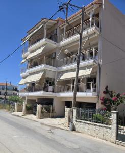 a tall white building with balconies on a street at NIMA Mytikas Apartments - Aitoloakarnania in Mitika