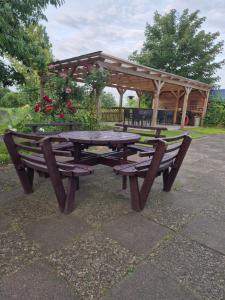 a picnic table and bench in front of a gazebo at Ferienwohnung zum Zander - Sonniger Weitblick übers Feld in Wester-Ohrstedt