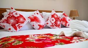 a bed with red and white pillows on it at La Maison Figaro Guest House - Spacious Island Stay in La Digue in La Réunion