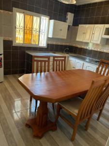 a kitchen with a wooden table and chairs at Résidence el hachen in Djerba
