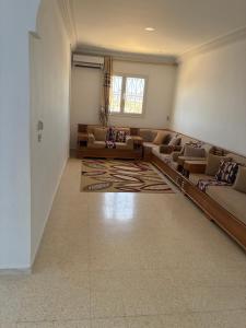 a large living room with couches and a rug at Résidence el hachen in Djerba