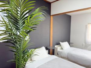 a bedroom with two beds and a palm plant at ura 花れ -hanare- in Okayama