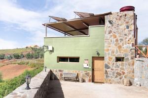 a green building with a wooden door and a bench at El Alpendre in Moya