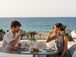 a man and a woman sitting at a table drinking wine at Creta Palace, A Resort to Live in Rethymno
