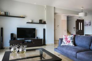 a living room with a blue couch and a tv at Villa Karavias by Villa Select in Trapezaki