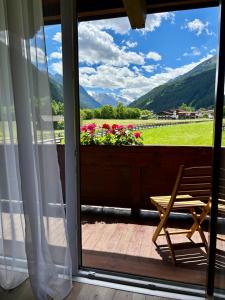 a wooden chair sitting on a porch with a window at Alpenhaus Monte Bike & Hike in Neustift im Stubaital
