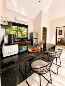 a kitchen with a black counter top and chairs at Mirari Villa in Wok Tum