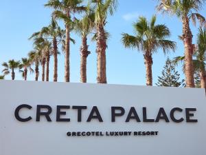 a sign with palm trees in the background at Creta Palace, A Resort to Live in Rethymno +131 photos