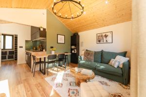 a living room with a green couch and a table at Le Chalet Madrier - Terrasse et Jacuzzi privé in Tours-en-Savoie