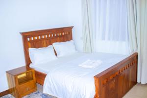 a bedroom with a large bed with a wooden headboard and a window at Chama Haven Appartment 2 bed in Tengeru