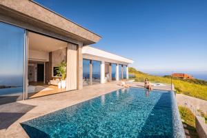 a swimming pool in a house with people sitting on the edge of it at Villa Platinum by Homie in Estreito da Calheta