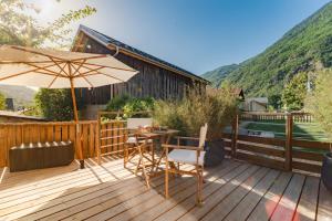 a wooden deck with a table and an umbrella at Le Chalet Madrier - Terrasse et Jacuzzi privé in Tours-en-Savoie