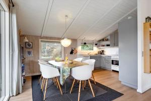 a kitchen with a dining room table and white chairs at 239-Ringkobing-Vestklitvej-32 in Klegod