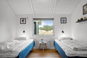 a bedroom with two beds and a window at 239-Ringkobing-Vestklitvej-32 in Klegod