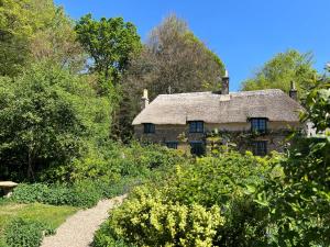 an old stone house in the middle of a garden at Wyndthorpe Cottage in Milton Abbas
