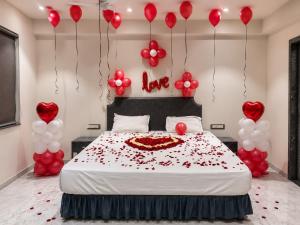 a bedroom with a bed with red hearts and balloons at Hotel Nee Residency in Rajkot