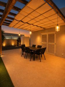 a patio with a table and chairs and lights at Aurea 1 Luxury House in Antigua