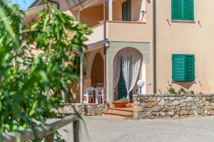 a house with green shutters and a stone wall at Appartamenti Le Solane - Goelba in Marmi
