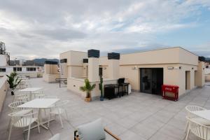 a patio with tables and chairs on a roof at Suiters Málaga in Málaga
