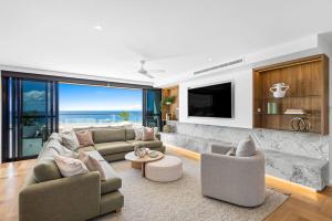 a living room with a couch and a tv at Penthouse at First Bay Coolum in Coolum Beach