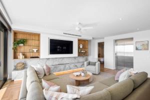 a living room with a couch and a tv at Penthouse at First Bay Coolum in Coolum Beach