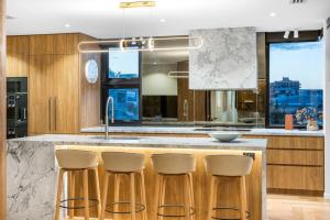 a kitchen with a counter with four bar stools at Penthouse at First Bay Coolum in Coolum Beach +28 photos