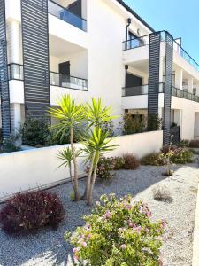 a building with palm trees and flowers in front of it at T2 confort - résidence privée in Propriano