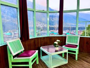 two chairs and a table in front of a large window at Hadimba Palace, Manali in Manāli