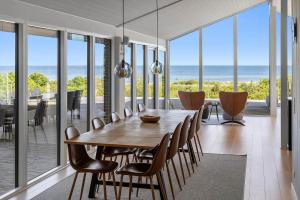 a dining room with a table and chairs and the ocean at 8535-Glesborg-Havstokken-12 in Glesborg
