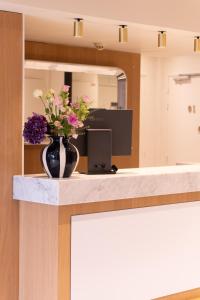 a vase filled with flowers sitting on a counter at Hotel Frochot Montmartre in Paris
