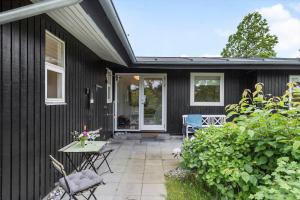 a black house with a patio and a table and chairs at 84159-Ebeltoft-Koravej-5 in Ebeltoft