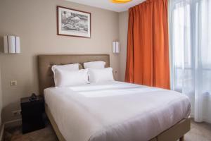 a bedroom with a large white bed with an orange curtain at Hotel Frochot Montmartre in Paris
